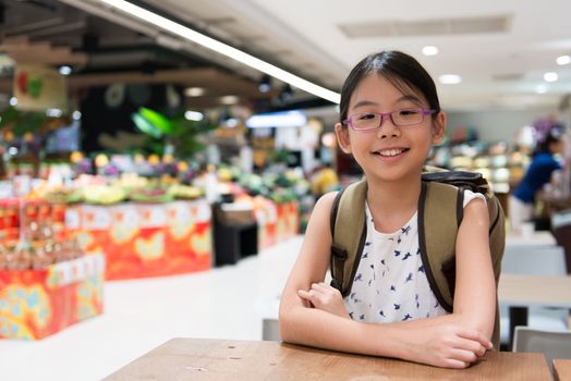 Portrait of beautiful Asian girl in a supermarket with backpack