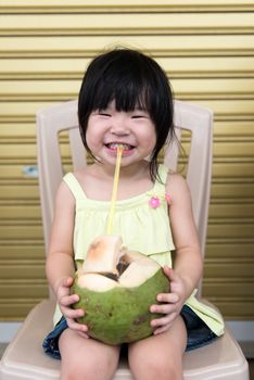 Cute little Asian child drinking coconut water
