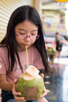 Cute little Asian child drinking coconut water