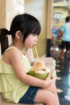 Cute little Asian child drinking coconut water