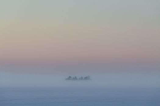 Winter landscape, where the lonely island is in the middle of the fog.