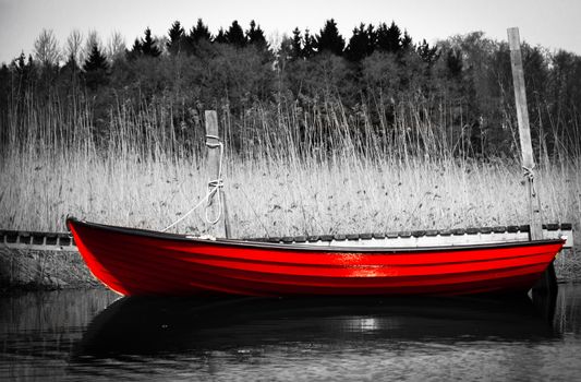 Red rowing boat otherwise in black and white picture. The picture is taken in Kotka, Finland.