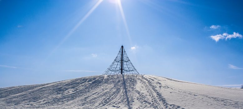 Winter image from Kotka, Finland, with a climbing frame on a snowy hill.