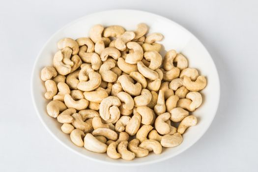 A plate full of cashew nuts. Photo taken on a white background.