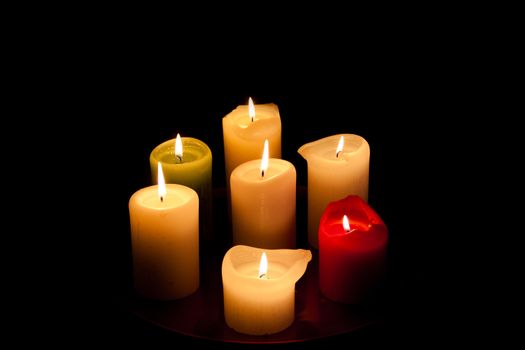 Seven candles on the table. The background is dark.