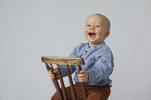 A happy boy sits in the chair. The cute kid is laughing.