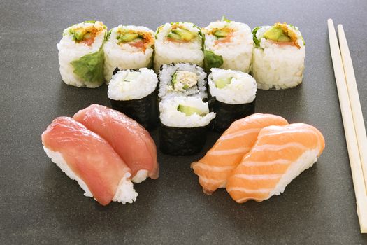 Plate of sushi rolls. Sushi set sashimi and sushi rolls served on wooden plate. Rolls with salmon, eel, tuna, avocado, royal prawn, cream cheese caviar tobica, chuka. Sushi menu. Japanese food.
