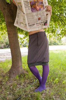 young woman reading a newspaper in the park