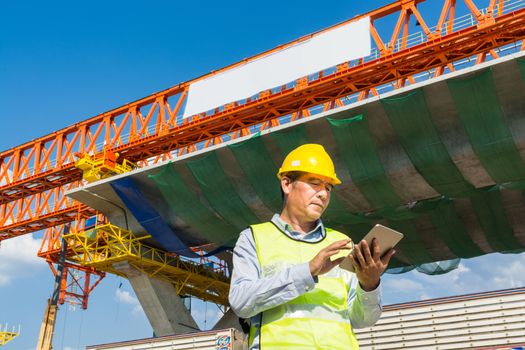Male Architect or Engineer working with Digital Wireless Tablet beside Autobahn or Expressway Construction site as Technology Project Development