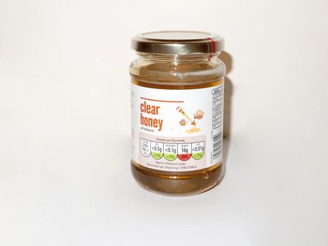 glass jar of basic clear honey white background food studio; essex; england; uk