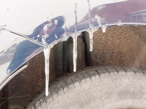 hanging icicles of water frozen on car above tire; essex; england; uk