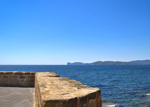 panorama of the sea from the ramparts of Alghero with the promontory of Capo Caccia in the distance in a sunny summer day