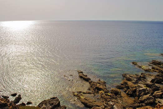 view of the sea with the sun in backlight and the rocks in the foreground