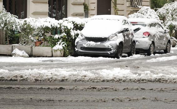 cars parked in the city almost completely covered with snow. winter and cold temperature concept