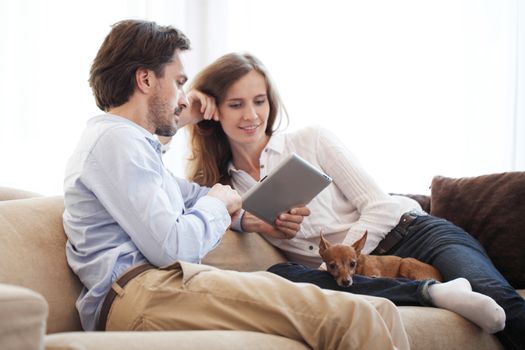 Cheerful couple using digital tablet at home