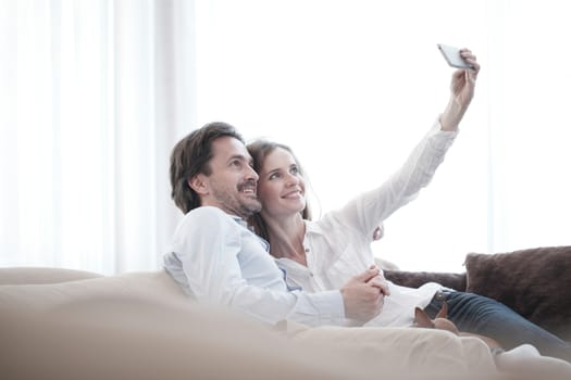 Happy couple taking a selfie together on the couch at home