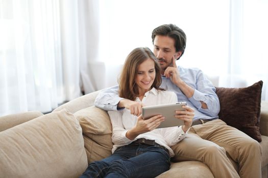 Cheerful couple using digital tablet at home