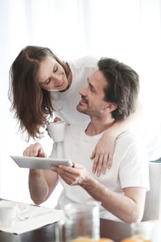 Couple having breakfast at home and using tablet