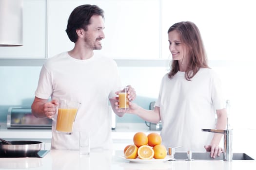 Couple with orange juice in the kitchen