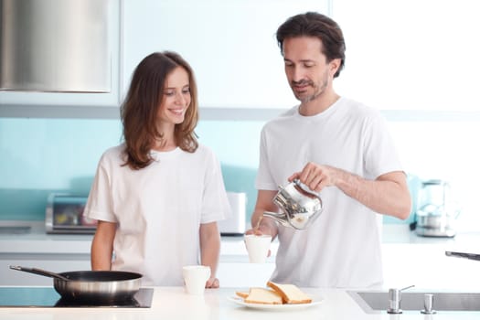 Happy couple cooking breakfast together in the kitchen