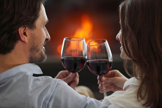 Romantic couple drinking wine at home near fireplace