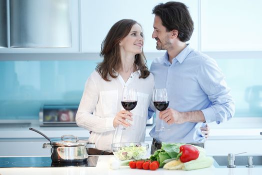 Portrait of a couple having a glass of red wine while cooking dinner