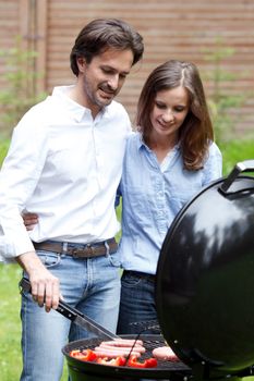 Happy couple cooking food on barbecue