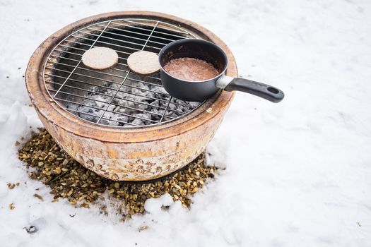 Barbeque snacks using a fire bowl in cold winter snow.