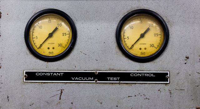 Vintage antique automotive machine shop vacuum gauges on a silver sheet metal plate with sign