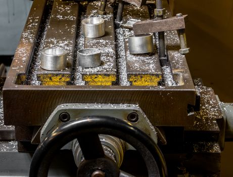 Vintage antique automotive machine shop milling table with aluminum machined components and filings with an adjustment wheel