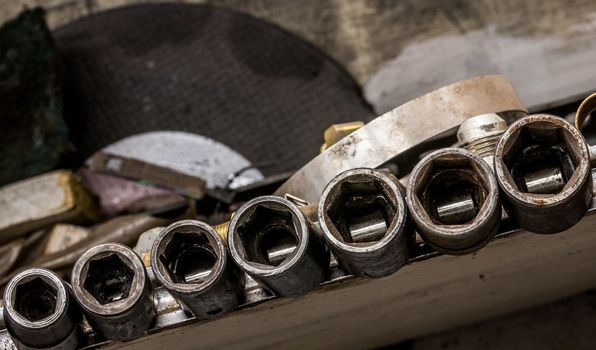 Vintage antique automotive machine shop hardened well used steel shallow impact socket set on a dirty work bench shelf