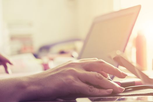 Close-up of female hands using laptop computer, working on laptop with flare light background. Searching Internet ,Businesswoman working at home office