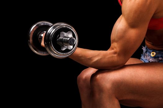 Fitness woman with dumbbell posing against black background, isolated