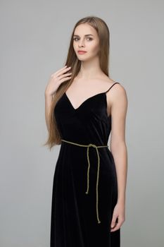 Young beautiful long-haired girl stands in black dress
