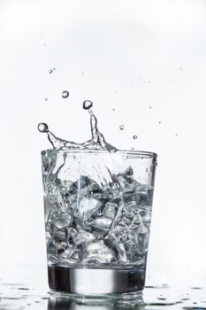 Glass with water and falling crystals of ice