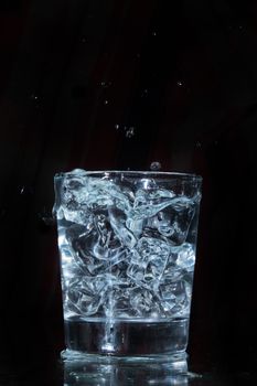 Glass with water and falling crystals of ice