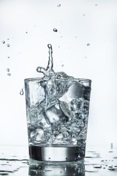 Glass with water and falling crystals of ice