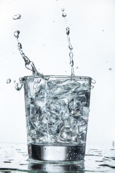 Glass with water and falling crystals of ice