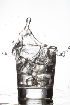 Glass with water and falling crystals of ice