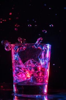 Glass with water and falling crystals of ice