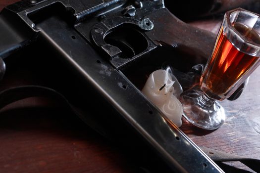 Old USA submachine gun closeup near glass of whiskey on wooden background