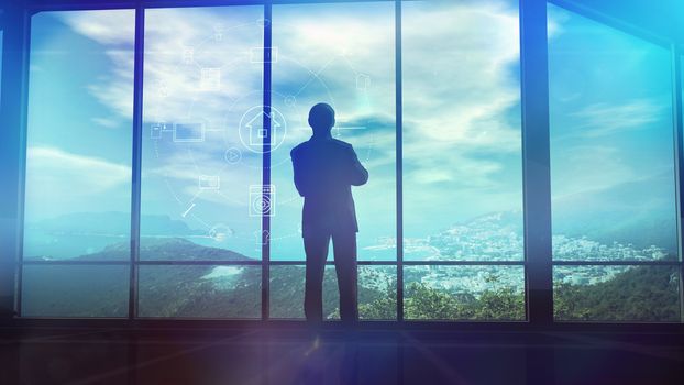 The picture illustrates a modern house and standing against a large window man. He is viewing the control interface of his smart home.