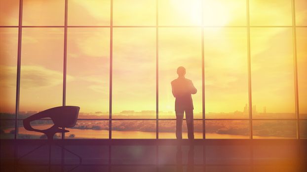 Silhouette of a man in a huge office in front of large windows.
