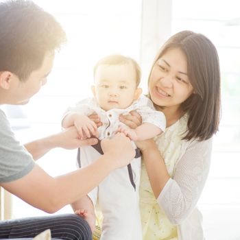 Happy Asian family at home, parents and baby, natural living lifestyle indoors.