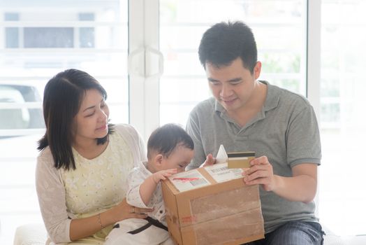 Online purchase with credit card. Happy Asian family at home, natural living lifestyle indoors.