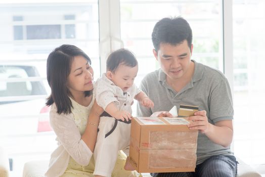 Online shopping with credit card. Happy Asian family at home, natural living lifestyle indoors.