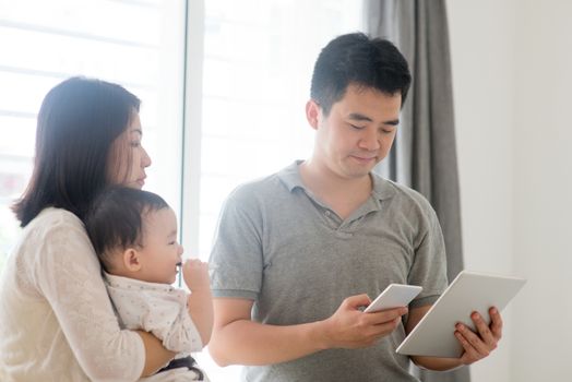 Chinese father scanning QR code with smart phone. Asian family at home, natural living lifestyle indoors.