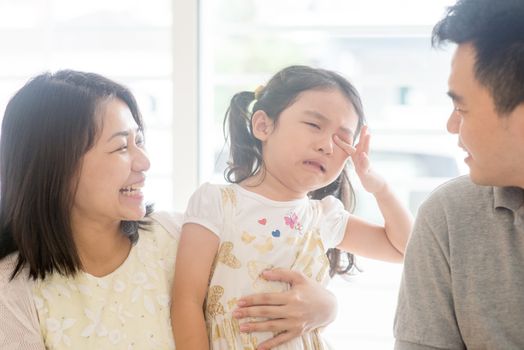 Father and mother  comforting crying daughter. Asian family at home, natural living lifestyle indoors.