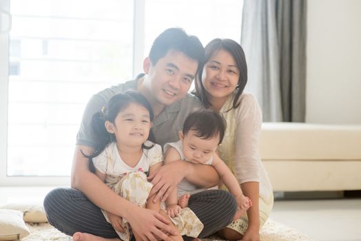 Parents and children sitting on floor together. Happy Asian family spending quality time at home, natural living lifestyle indoors.