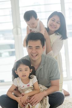 Parents and children sitting on floor. Happy Asian family spending quality time at home, natural living lifestyle indoors.